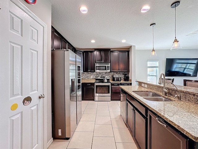 kitchen with pendant lighting, sink, light tile patterned floors, stainless steel appliances, and dark brown cabinetry