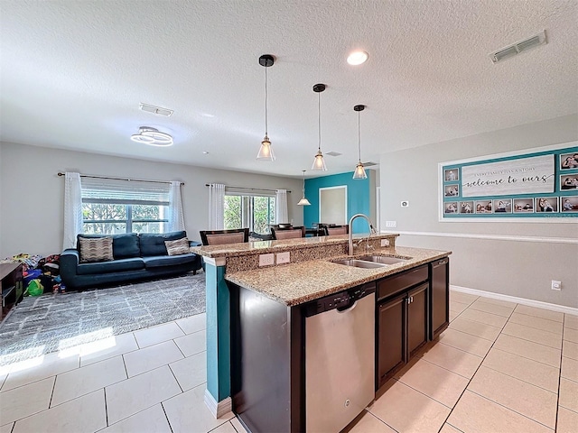 kitchen with sink, light tile patterned floors, hanging light fixtures, light stone countertops, and stainless steel dishwasher