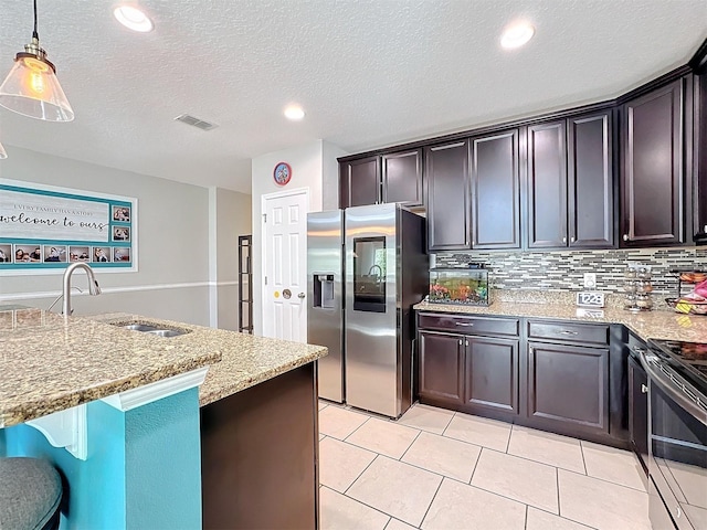 kitchen featuring sink, hanging light fixtures, stainless steel appliances, dark brown cabinetry, and light stone countertops