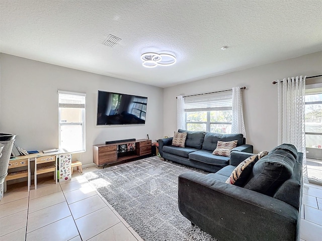 living room with a healthy amount of sunlight, light tile patterned floors, and a textured ceiling