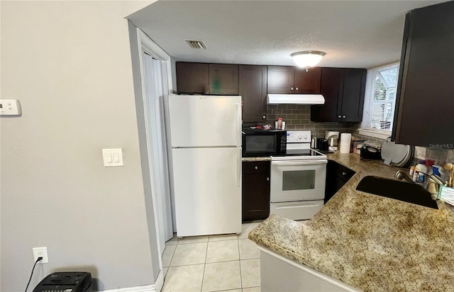 kitchen featuring light tile patterned flooring, dark brown cabinetry, sink, white appliances, and light stone countertops