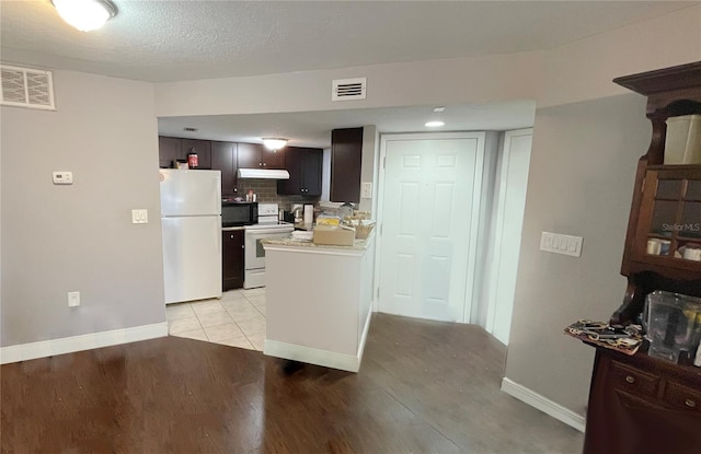 kitchen featuring white appliances, backsplash, dark brown cabinetry, a textured ceiling, and light wood-type flooring