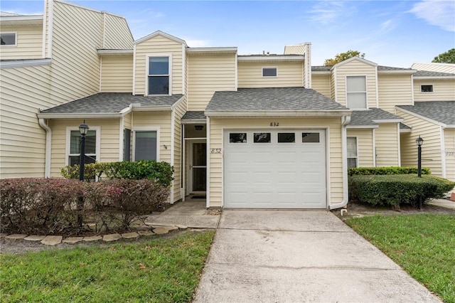 multi unit property featuring a garage, driveway, and roof with shingles