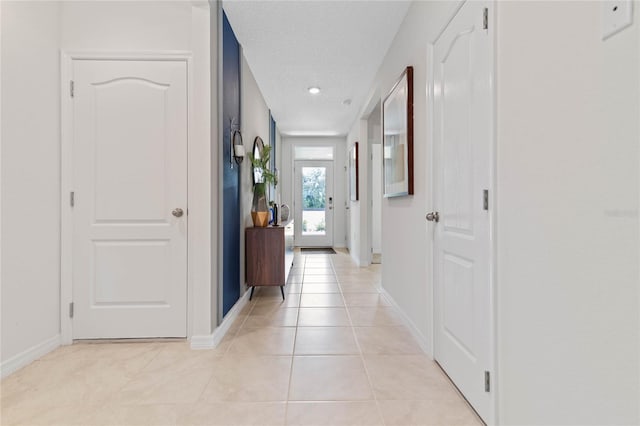 corridor featuring light tile patterned flooring and a textured ceiling