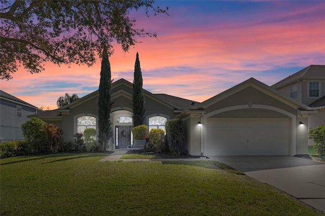 view of front of property featuring a garage, a front yard, concrete driveway, and stucco siding