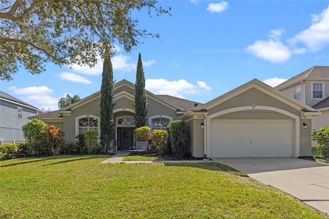 view of front of property featuring a garage, driveway, a front lawn, and stucco siding