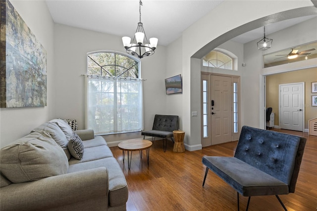 living area with a wealth of natural light, baseboards, arched walkways, and wood finished floors