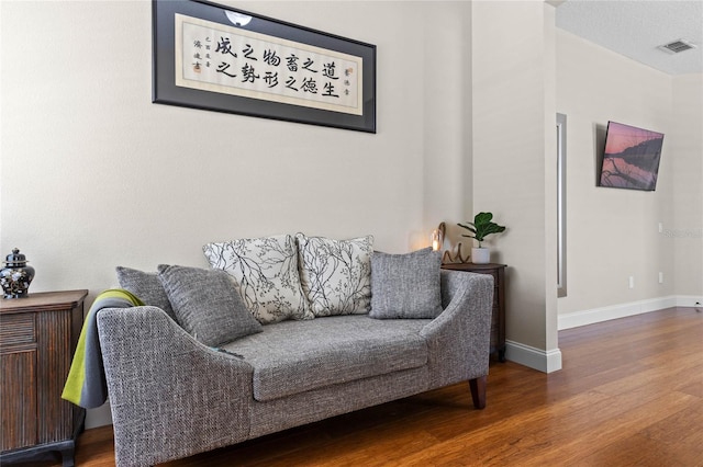 living area featuring visible vents, baseboards, and wood finished floors