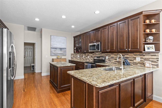 kitchen with visible vents, appliances with stainless steel finishes, light wood-style floors, a sink, and a peninsula