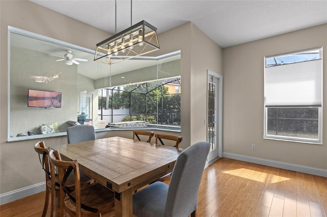 dining room featuring ceiling fan, wood-type flooring, a sunroom, and baseboards