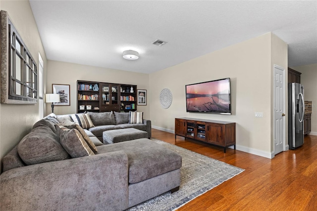 living area featuring visible vents, baseboards, and wood finished floors