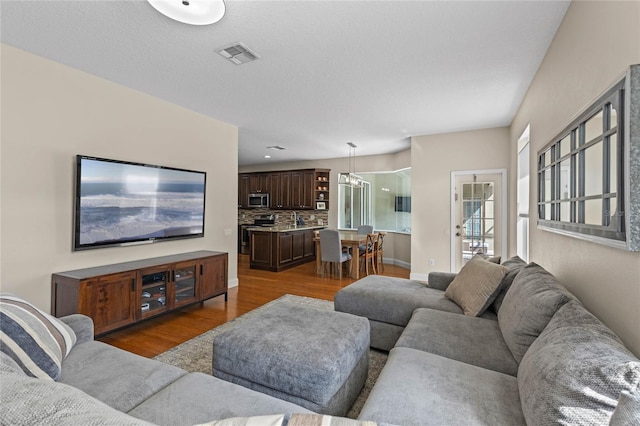 living room featuring baseboards, visible vents, and wood finished floors