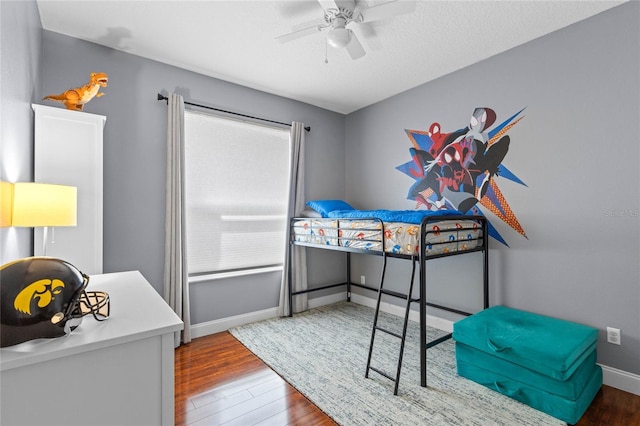 bedroom featuring a ceiling fan, a textured ceiling, baseboards, and wood finished floors