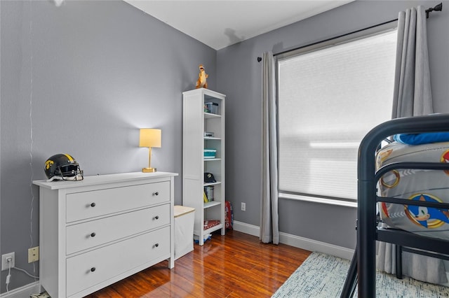 bedroom with dark wood finished floors and baseboards