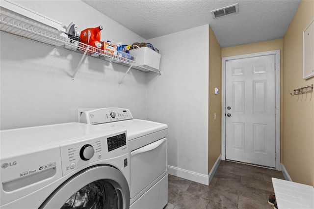 laundry room featuring laundry area, baseboards, visible vents, a textured ceiling, and washer and dryer