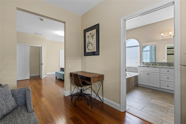 interior space featuring vanity, a textured ceiling, a bath, and hardwood / wood-style flooring