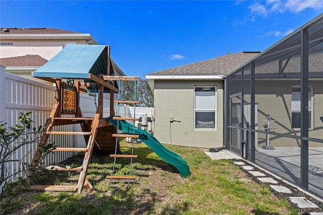 view of playground featuring glass enclosure and fence