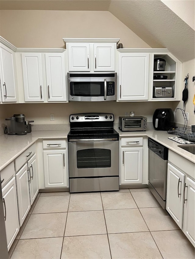 kitchen with light tile patterned flooring, white cabinets, and appliances with stainless steel finishes