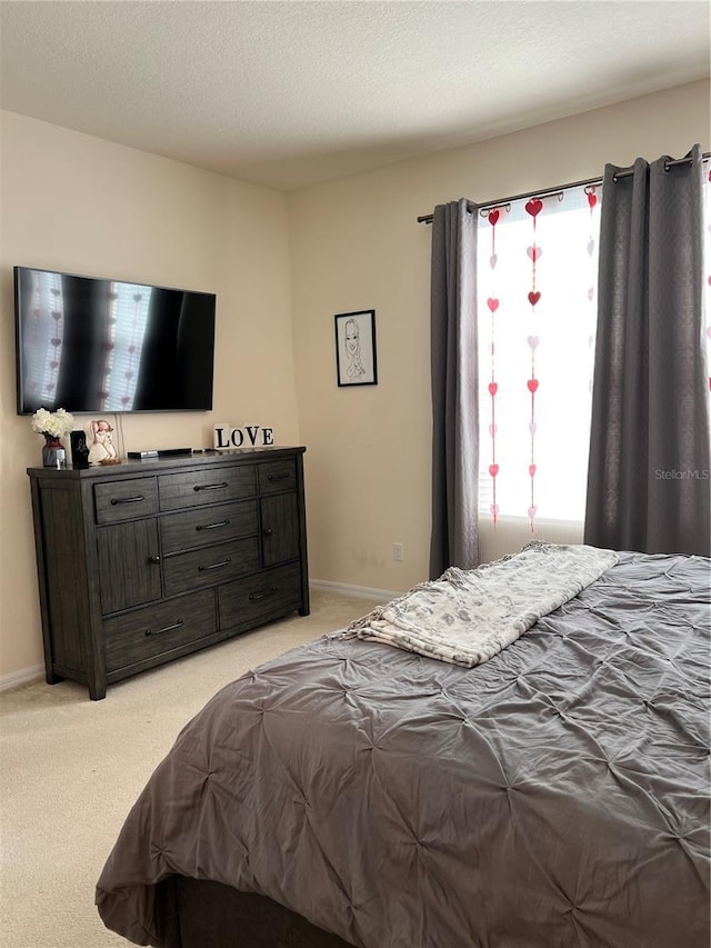 bedroom with light colored carpet and a textured ceiling