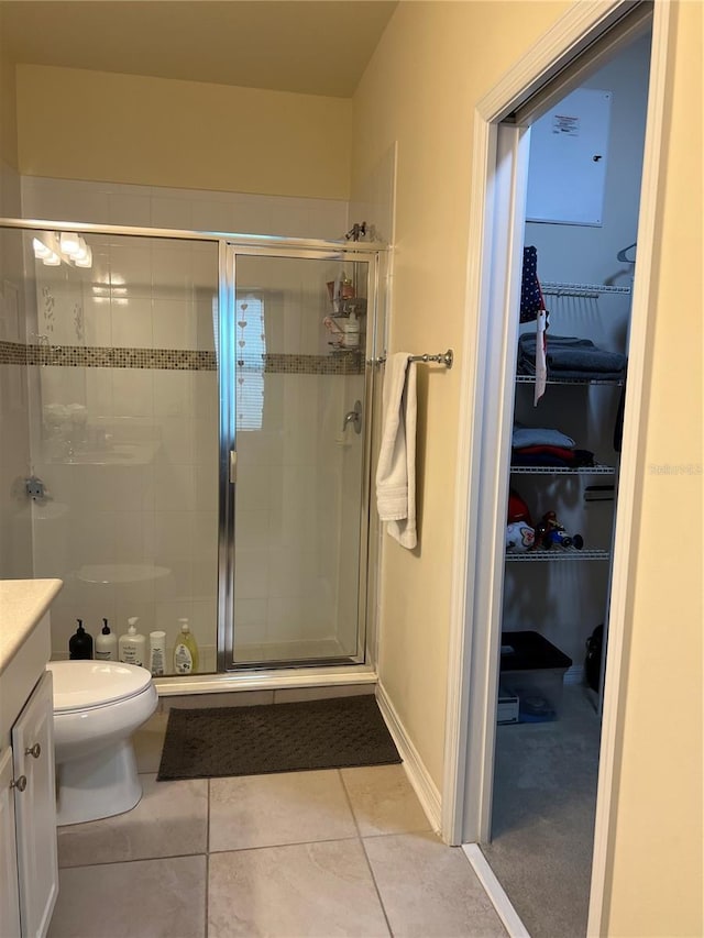 bathroom with a shower with door, vanity, tile patterned flooring, and toilet