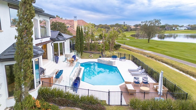 view of pool with a water view, a fenced backyard, and a yard