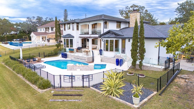 back of property with a balcony, a fenced backyard, and a lawn