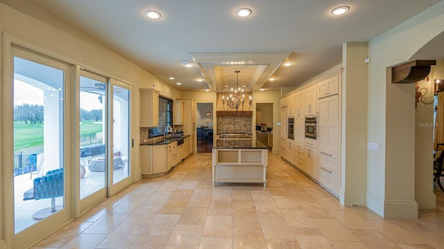 kitchen with recessed lighting, decorative backsplash, an inviting chandelier, appliances with stainless steel finishes, and a kitchen island with sink