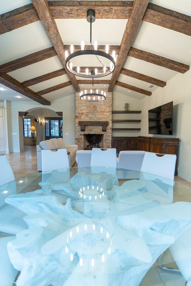 interior space featuring beam ceiling, a notable chandelier, and a stone fireplace