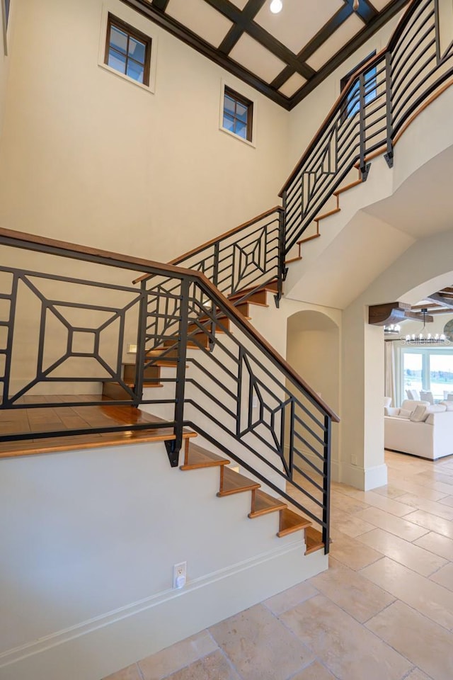 stairs with recessed lighting, coffered ceiling, a towering ceiling, and baseboards