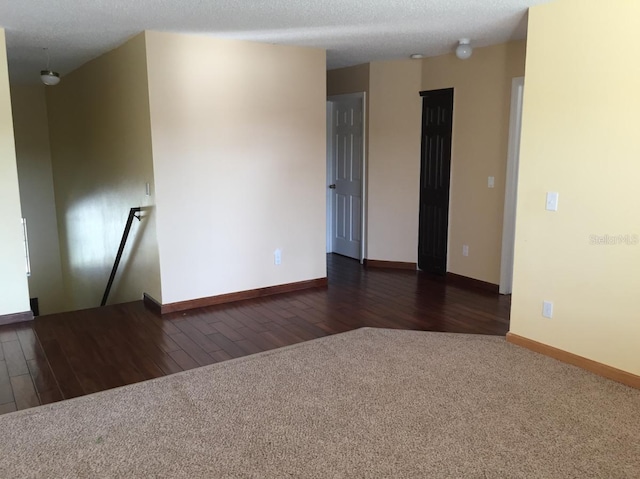 spare room with a textured ceiling and dark carpet