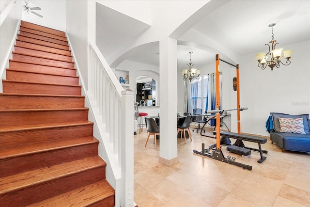 staircase with an inviting chandelier and arched walkways