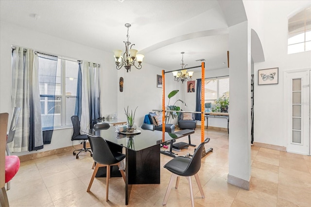 dining space with arched walkways, baseboards, and an inviting chandelier