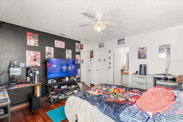 bedroom featuring a textured ceiling, dark wood-type flooring, visible vents, and a ceiling fan