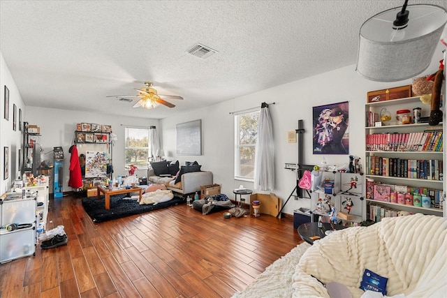 interior space featuring a ceiling fan, visible vents, dark wood finished floors, and a textured ceiling