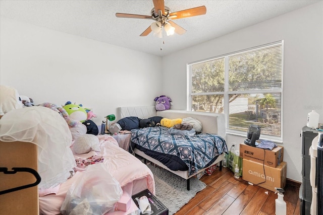 bedroom with ceiling fan, a textured ceiling, and wood finished floors