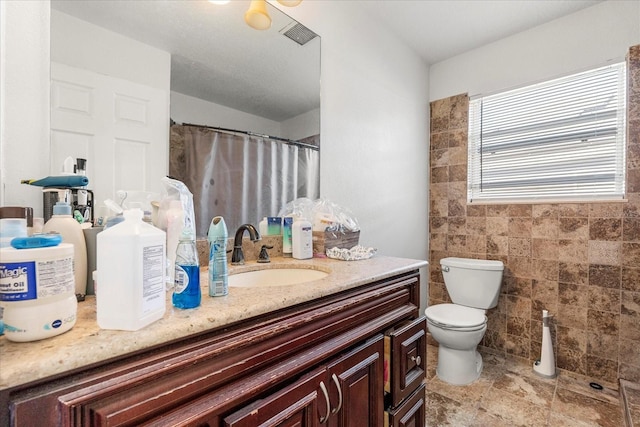 bathroom with tile walls, vanity, and toilet