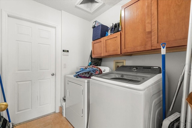 laundry area with washing machine and clothes dryer, light tile patterned floors, cabinet space, attic access, and a textured ceiling