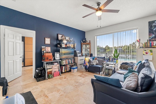 living area with a ceiling fan and a textured ceiling