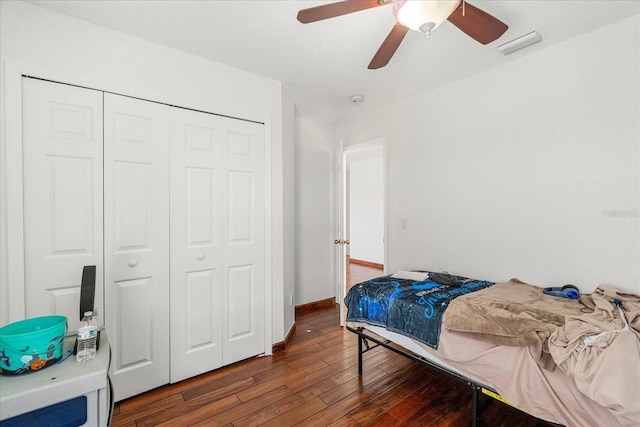 bedroom with dark wood finished floors, a closet, visible vents, ceiling fan, and baseboards