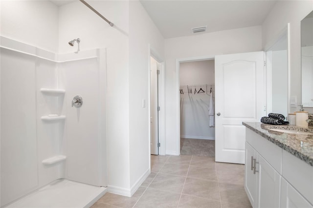 bathroom featuring vanity, tile patterned flooring, and a shower