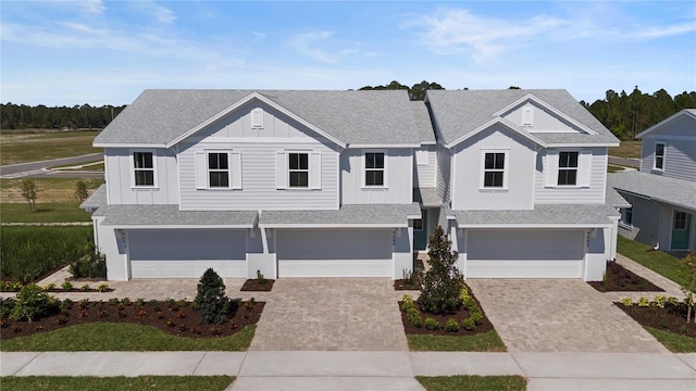 view of front facade featuring decorative driveway, an attached garage, board and batten siding, and a shingled roof