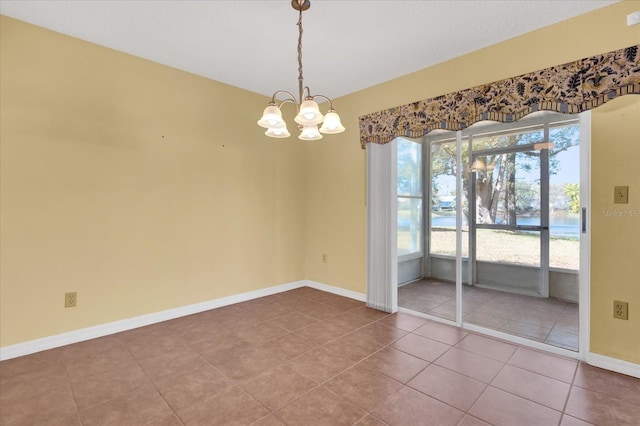 spare room featuring tile patterned floors and a chandelier