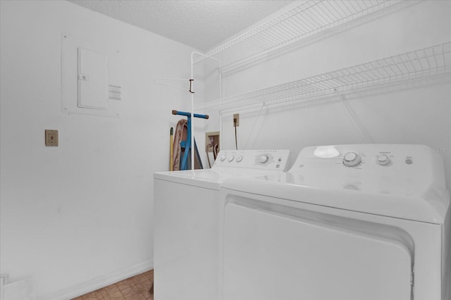 laundry room featuring electric panel, washer and dryer, and a textured ceiling