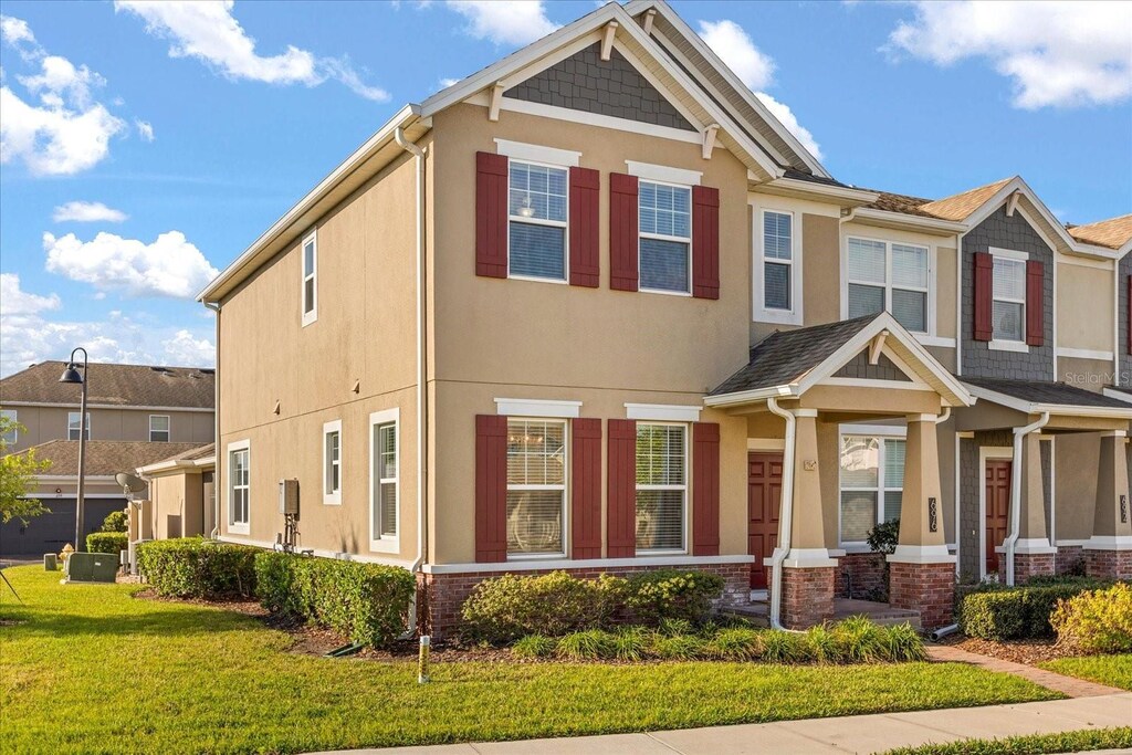 view of front facade featuring brick siding, stucco siding, and a front yard
