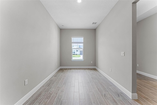 spare room featuring light hardwood / wood-style floors and a textured ceiling