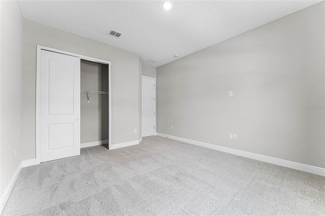 unfurnished bedroom featuring a closet and light carpet