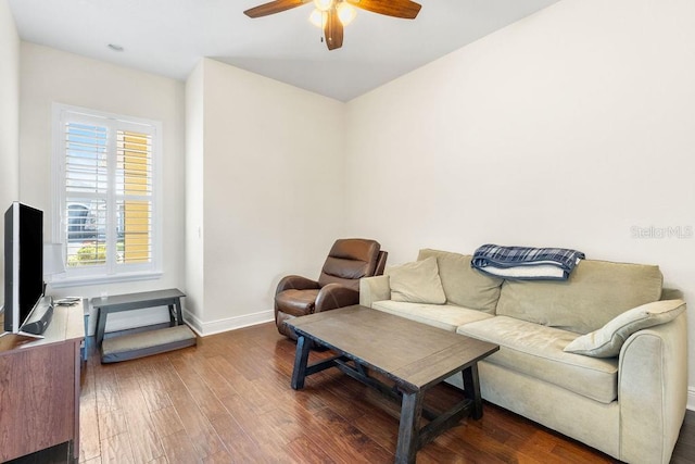 living room with a ceiling fan, baseboards, and wood finished floors