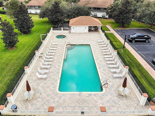 pool with a patio, a hot tub, and fence