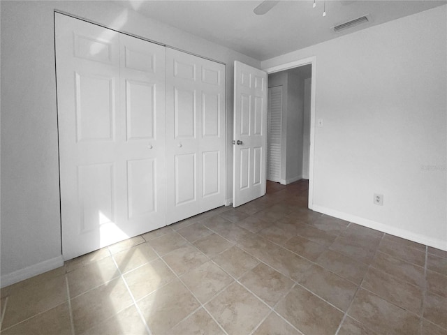 unfurnished bedroom with tile patterned floors, a closet, and ceiling fan