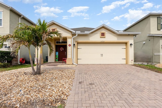 single story home featuring decorative driveway, a garage, and stucco siding